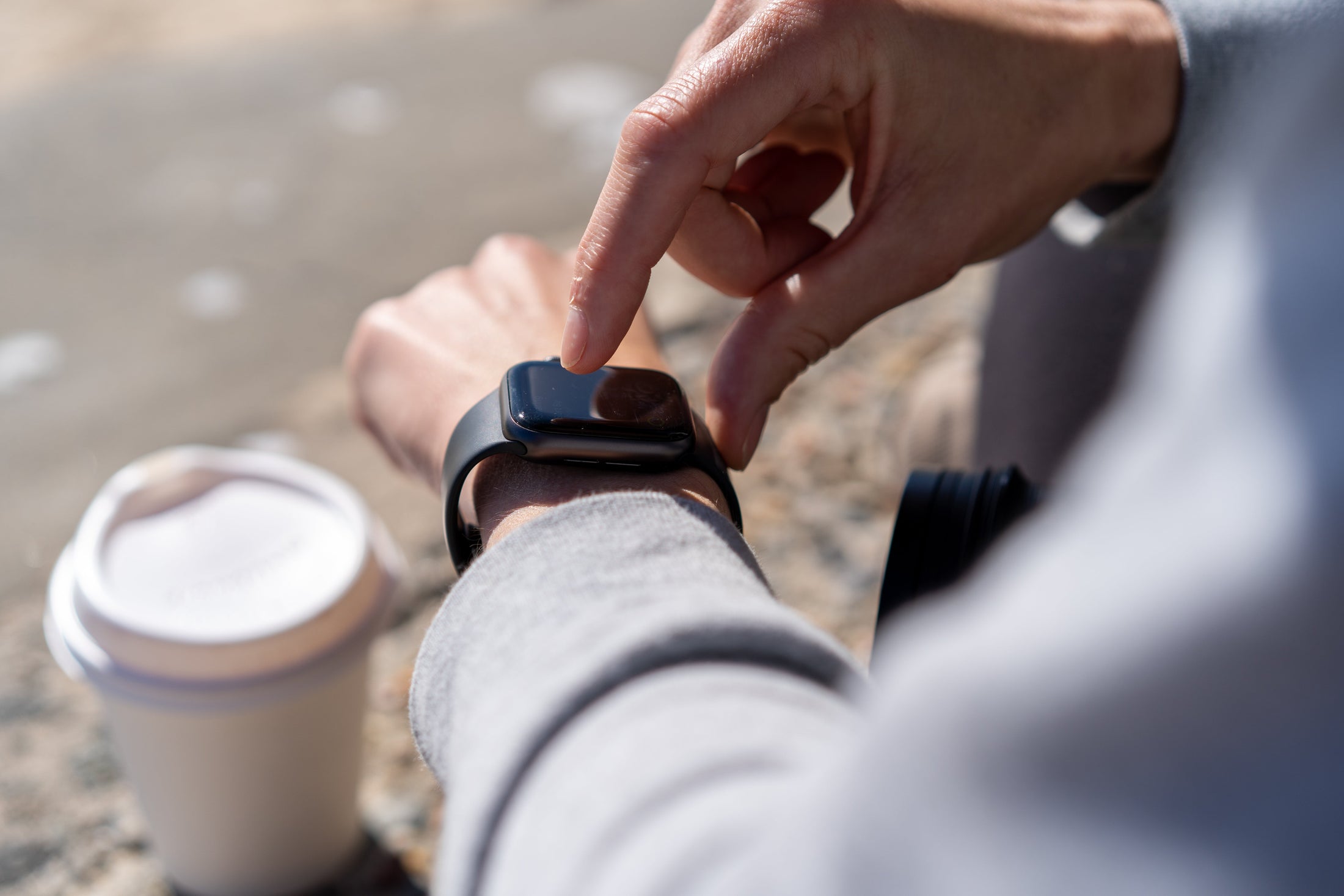 Visão de smartwatch com copo plástico de café ao fundo
